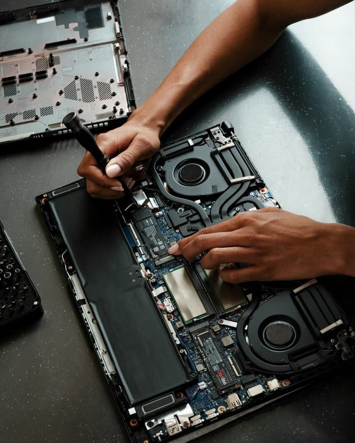 Lappytech technician using a screwdriver to repair a laptop's internal components on a workbench