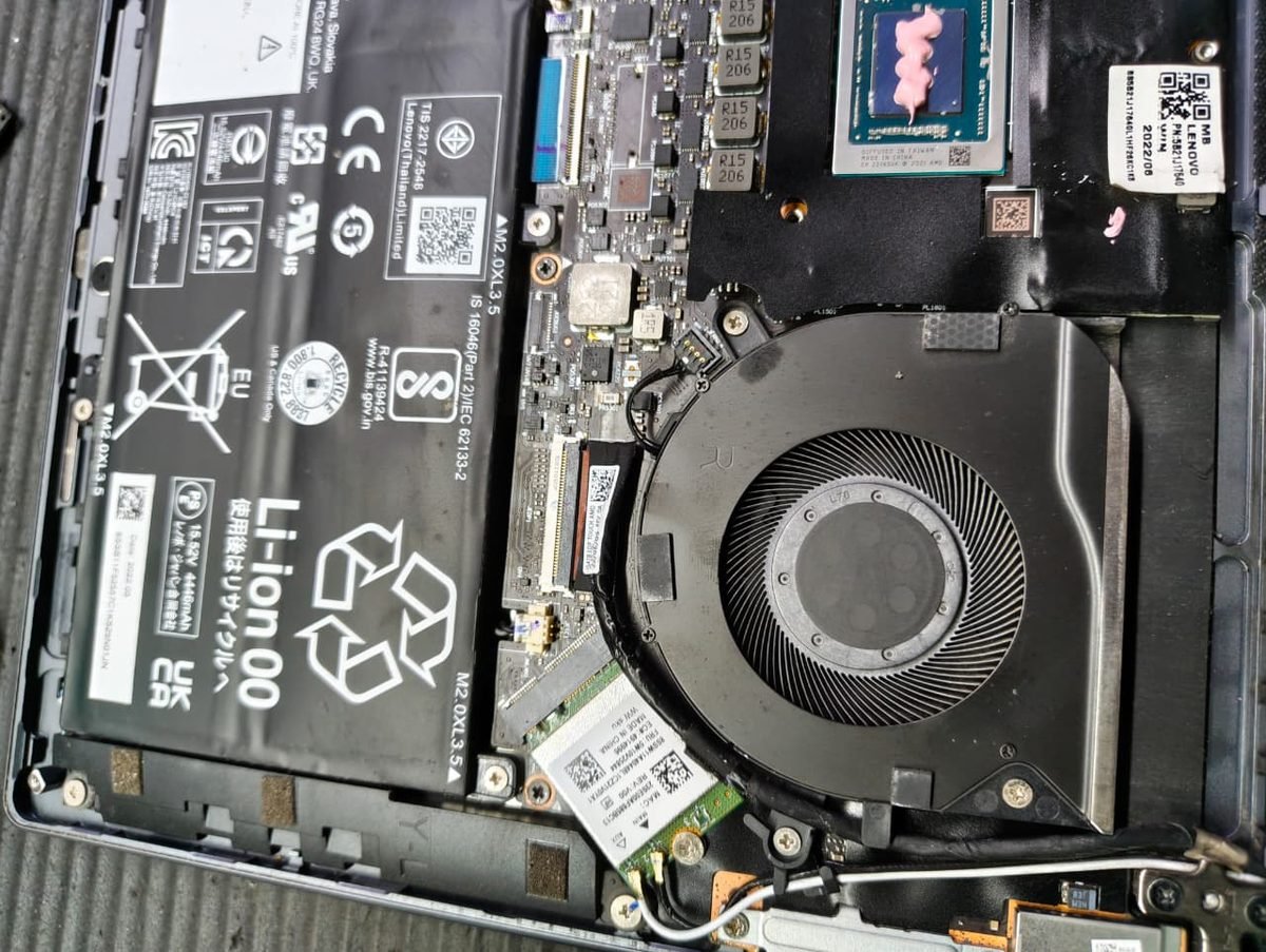Interior of a Lenovo laptop after servicing, with a clean fan assembly and freshly applied thermal paste on the CPU