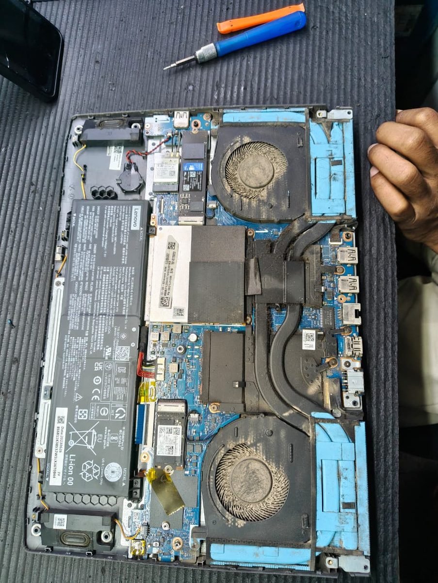 Interior of a Lenovo gaming laptop before servicing, with both cooling fans and heat sinks heavily clogged with dust